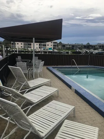 Waterfront outdoor swimming pool with a surrounding paver patio and a covered seating area