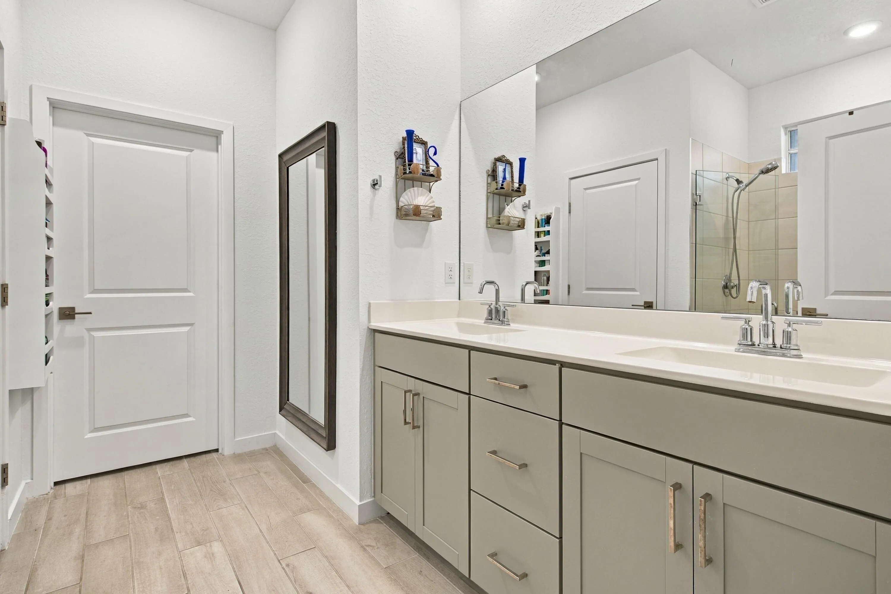 Primary bathroom with luxury wood like tiles, recessed lights, double sinks with draws