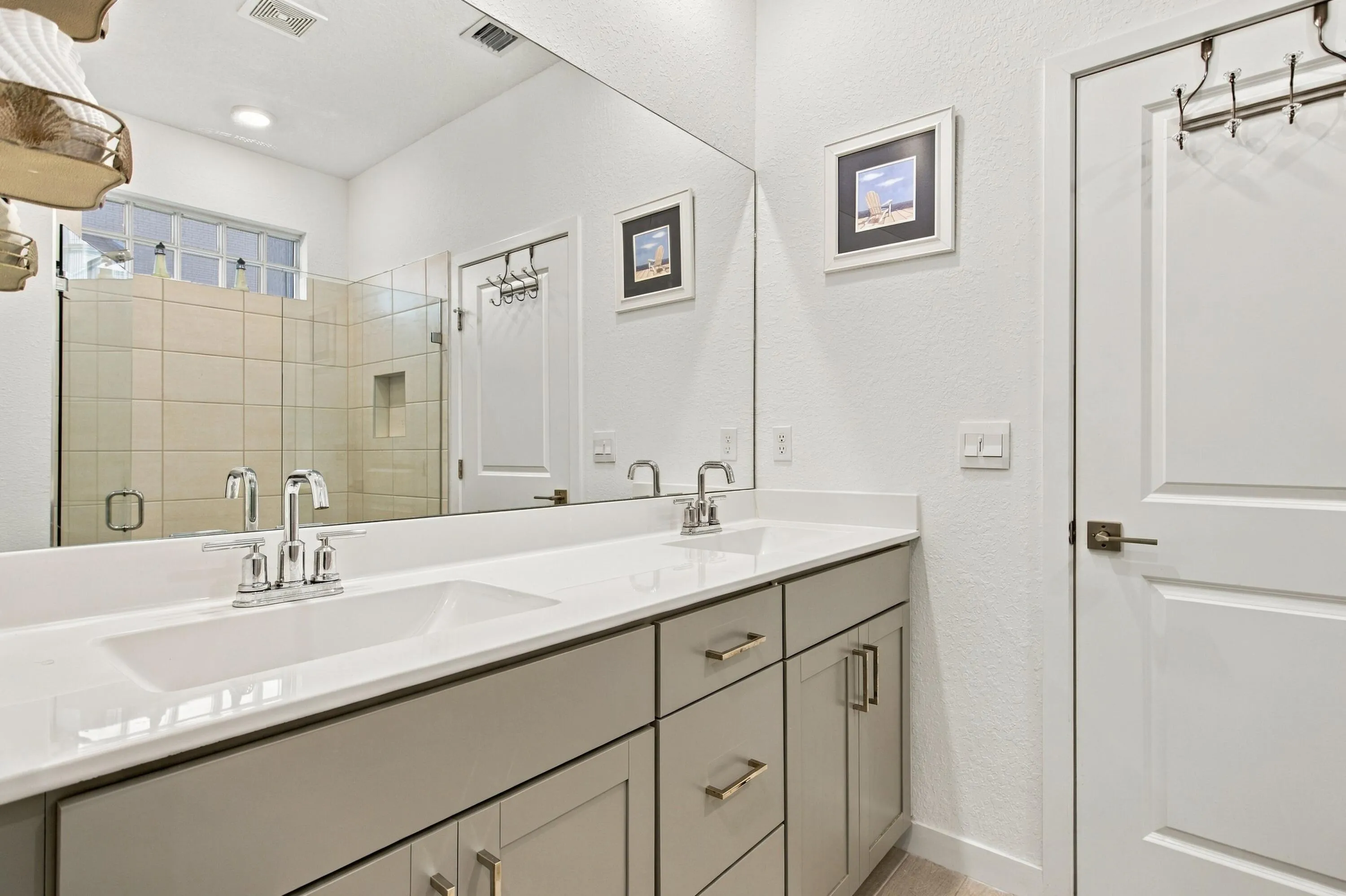 Double vanity in primary bathroom with newer light fixture