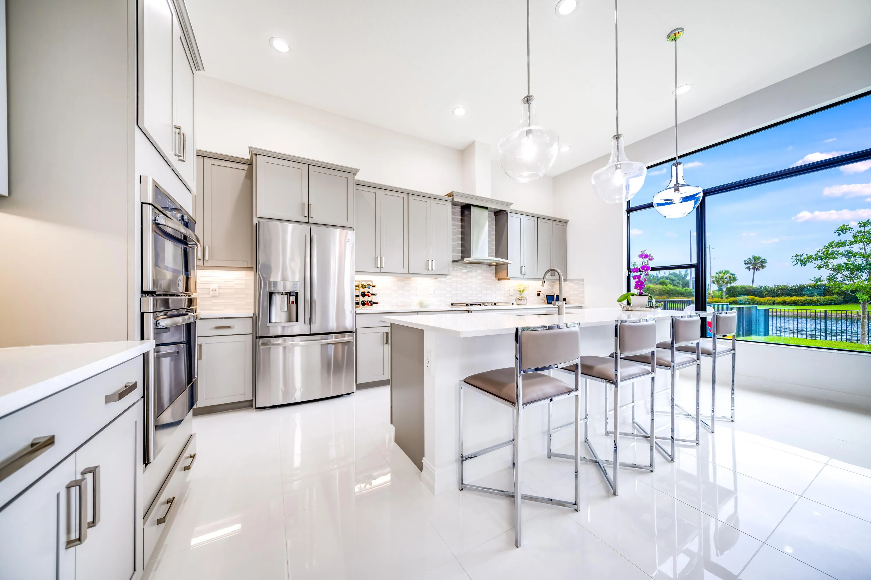 Kitchen featuring light gray cabinetry, stainless steel appliances, a center island with countertop seating, and a large picture window