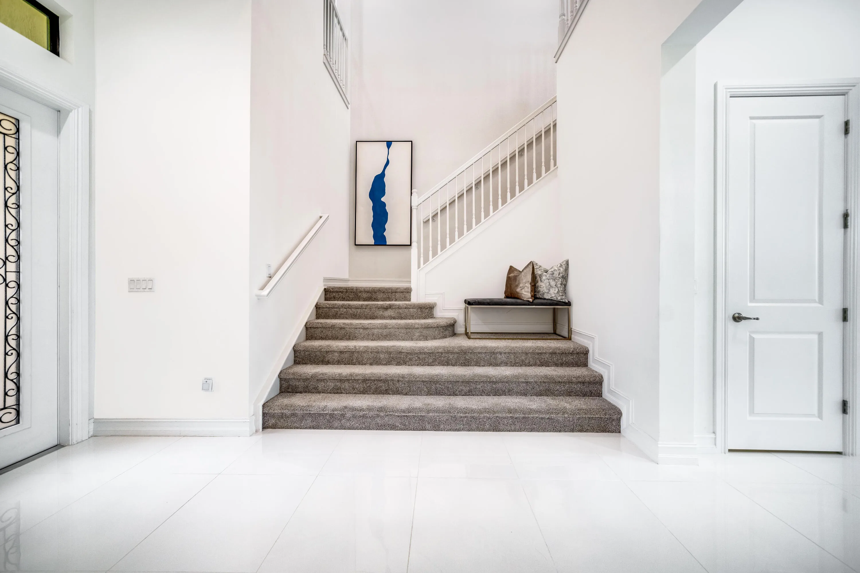 Spacious foyer with light-toned flooring and a white paneled door