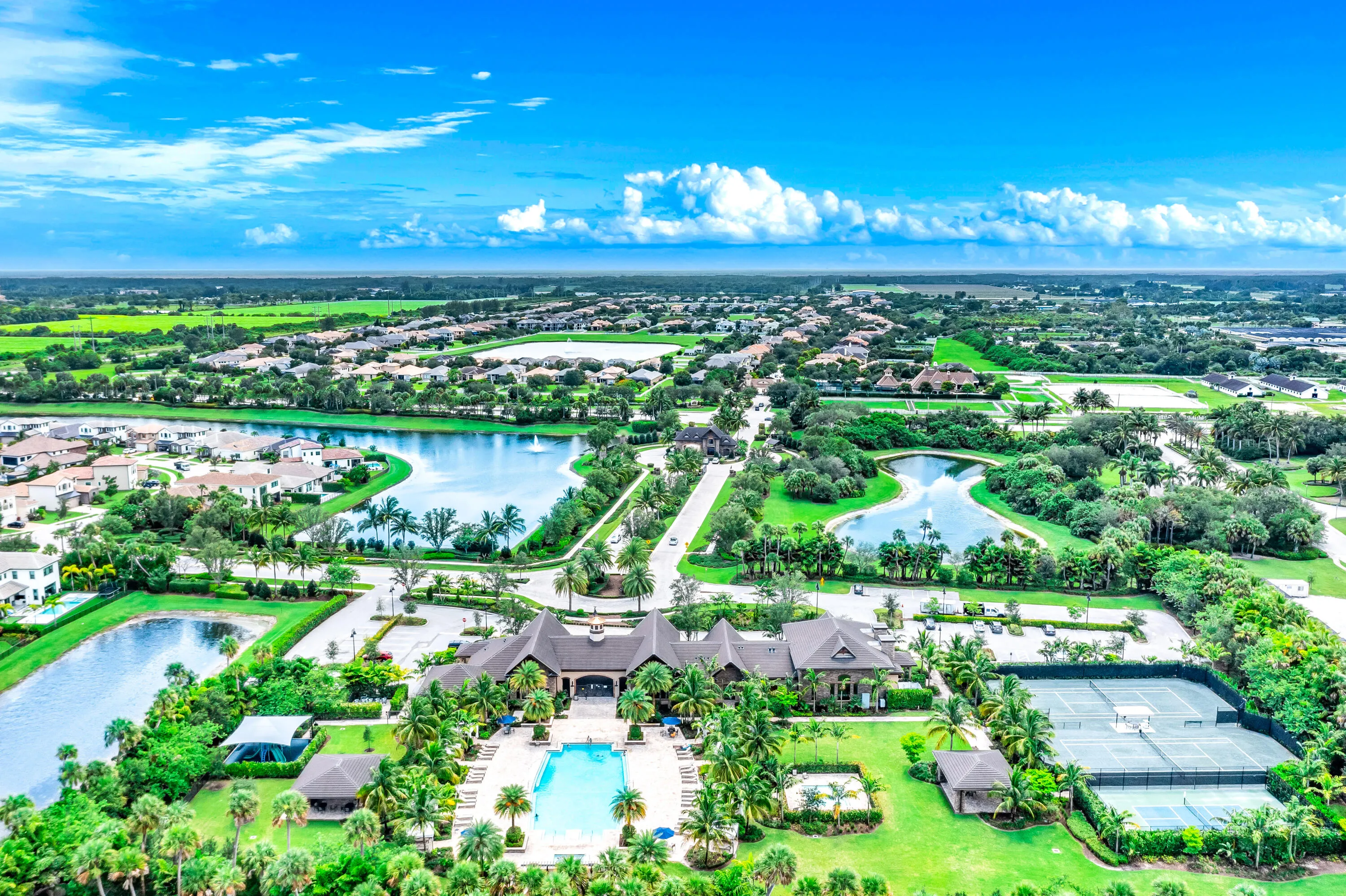Community clubhouse with an outdoor swimming pool, multiple tennis courts, and surrounding water features