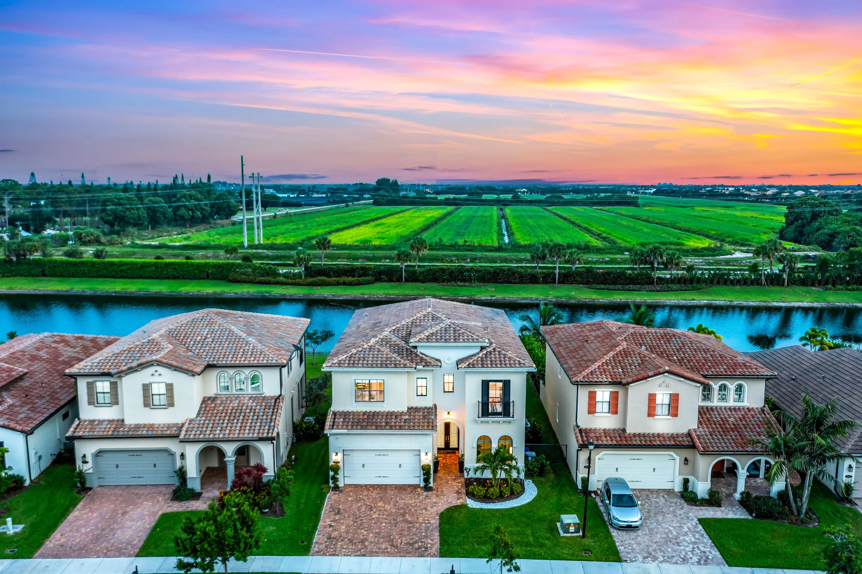 Waterfront property featuring tile roofs, stucco exteriors, and a manicured lawn