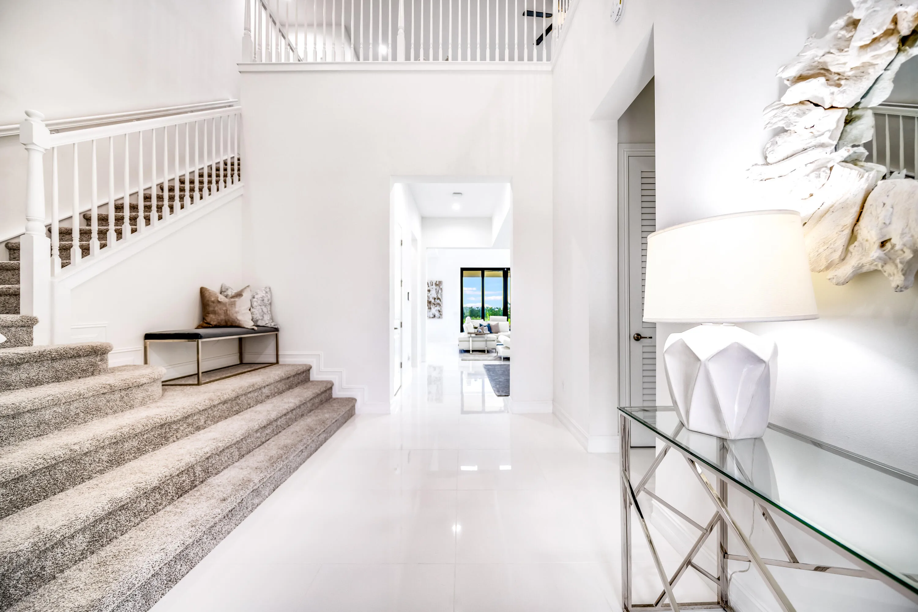 Two-story entry featuring white walls, a carpeted staircase with white balusters, and polished tile flooring