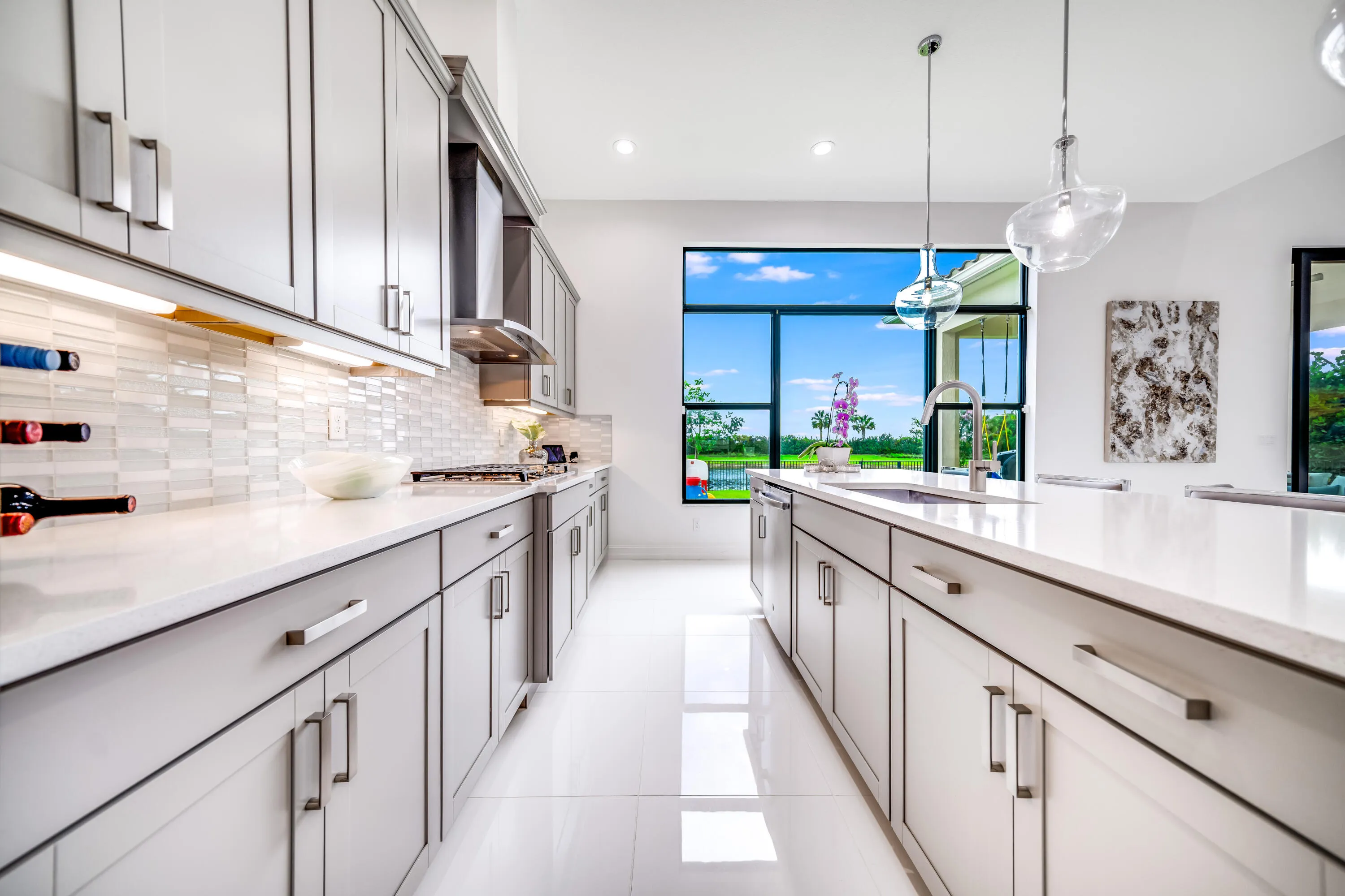Modern kitchen featuring gray cabinetry, light countertops, a tile backsplash, and a large window
