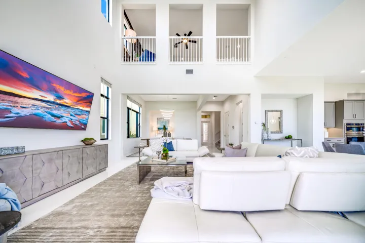 Soaring ceilings with upper-level balconies, expansive windows, recessed lighting, and a contemporary built-in media console