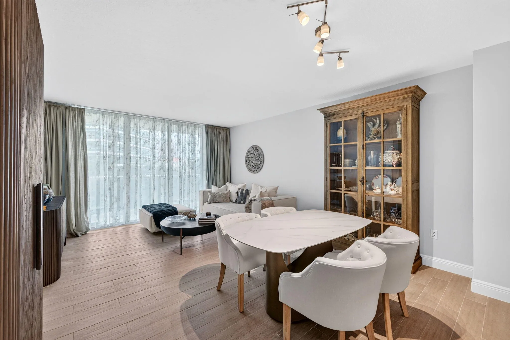Open-concept living and dining area featuring wide-plank tile -finish flooring, full-height glass doors, and a modern track lighting fixture