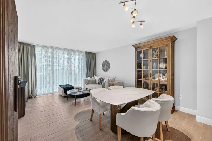 Open-concept living and dining area featuring wide-plank tile -finish flooring, full-height glass doors, and a modern track lighting fixture