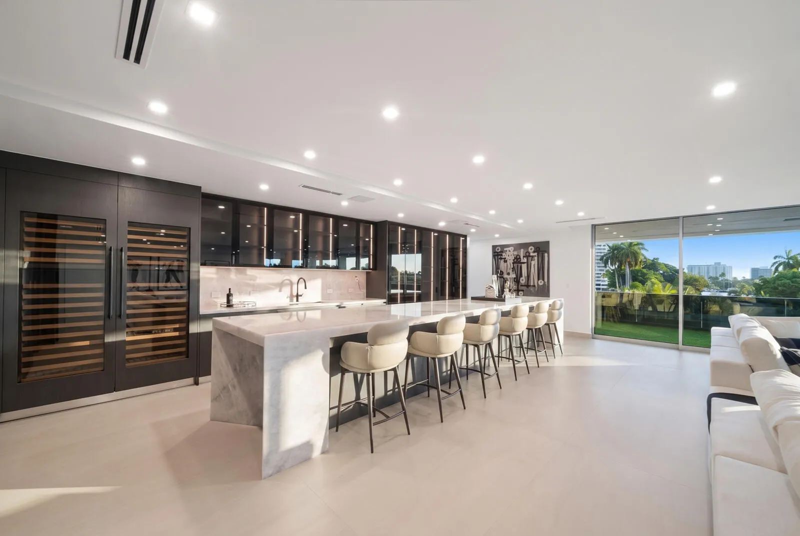 Showpiece 20-foot illuminated onyx bar featuring generous seating, custom smoked-glass cabinetry, dual wine storage, and sweeping skyline views.