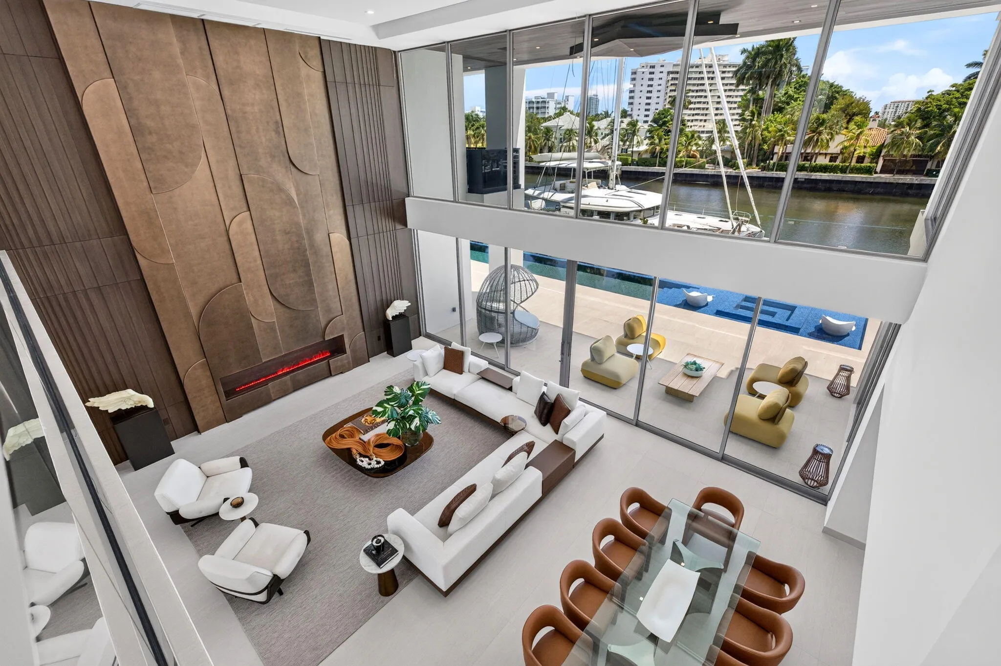 Second-floor view overlooking the dramatic two-story great room, infinity-edge pool, and waterfront beyond.