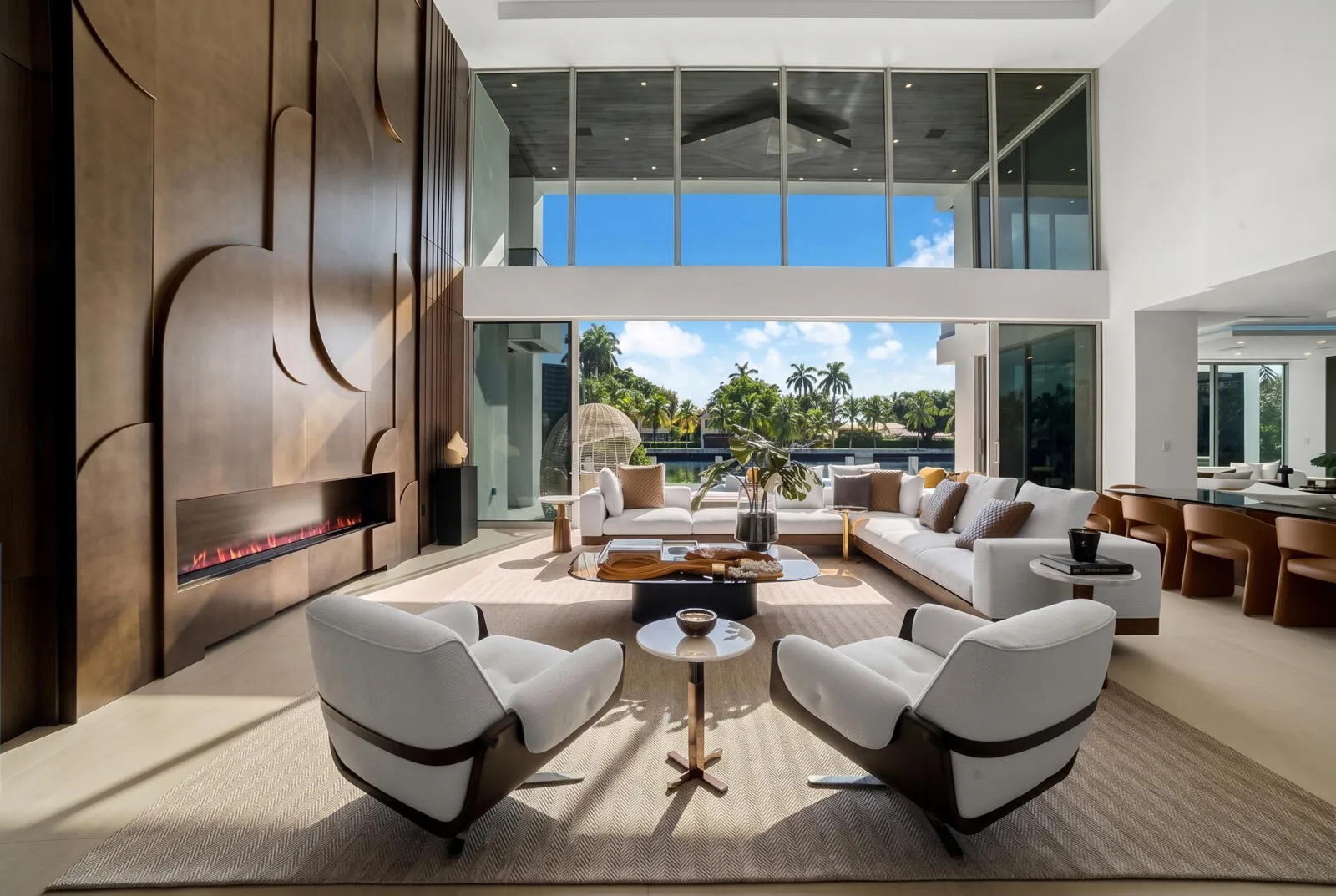 Sun-filled waterfront great room featuring floor-to-ceiling glass, refined designer furnishings, and seamless views of the pool and canal.
