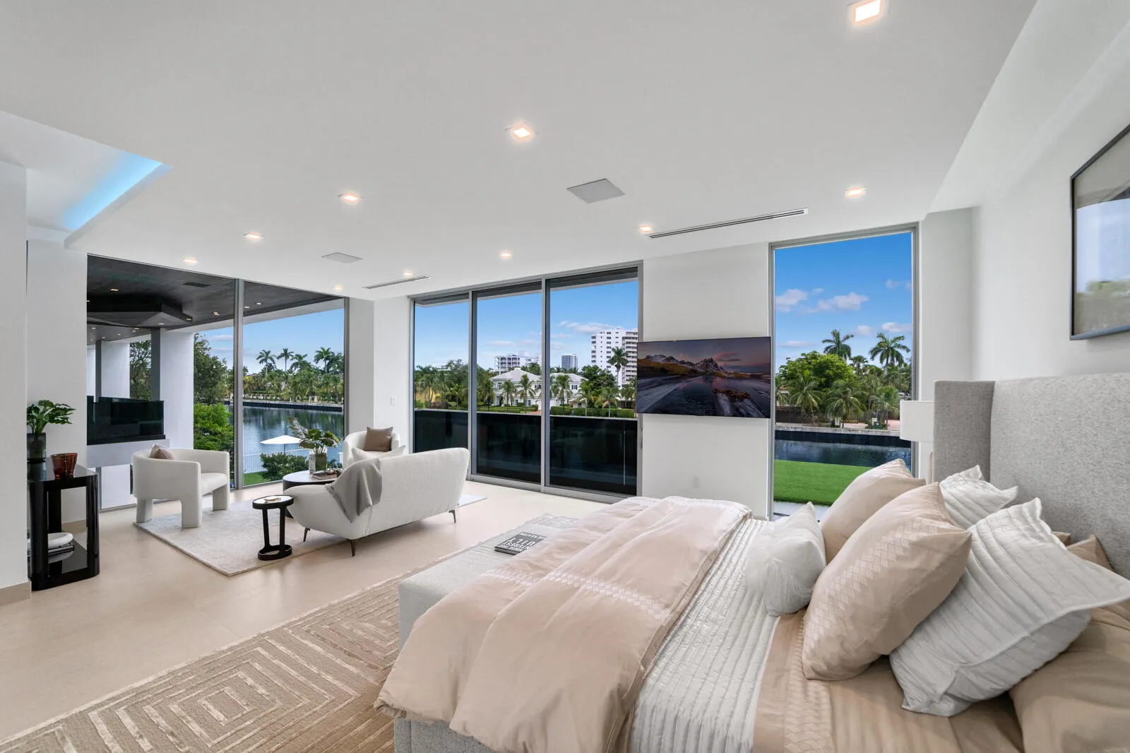 Private primary retreat with floor-to-ceiling glass framing sweeping canal and skyline views from the bedroom and adjoining sitting area.