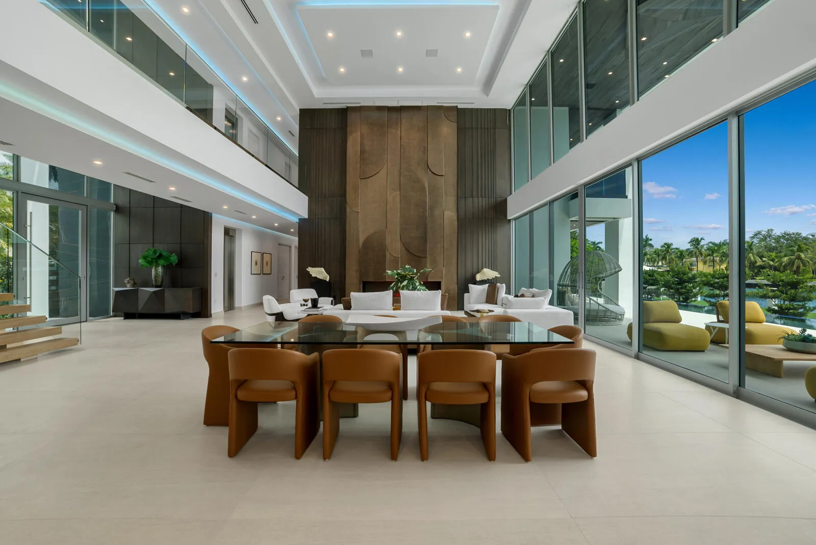 Elegant dining area surrounded by floor-to-ceiling glass, overlooking the waterfront and anchored by the magnificent three-level paneled fireplace wall.