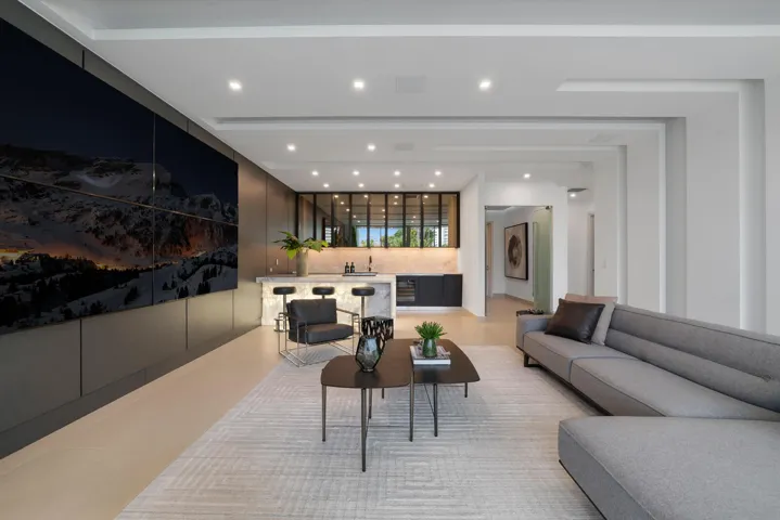 Exceptional first-floor VIP guest suite featuring a spacious private lounge, oversized media wall, full bar, designer finishes, and a private bedroom and bath.
