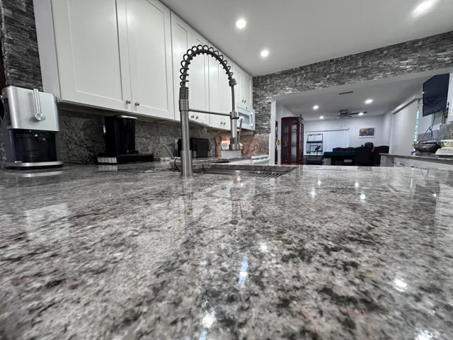 Kitchen granite detail at the island bar with sink, granite backsplash.