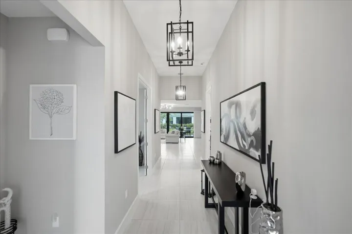 Long hallway featuring recessed lighting and three suspended black metal chandeliers