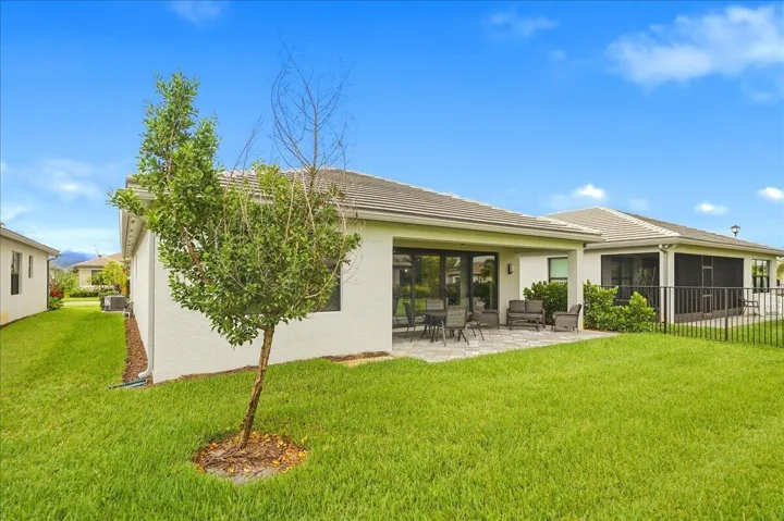 Expansive backyard featuring a paver patio, screened lanai, and lush green lawn