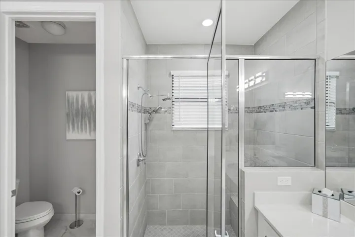 Glass-enclosed shower with subway tile surround, mosaic accent tile, and a built-in shower niche
