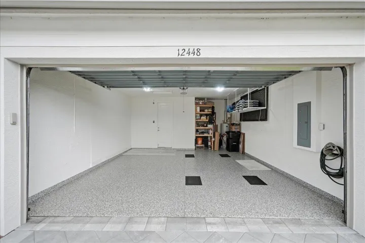 Spacious garage featuring a durable epoxy floor finish, overhead lighting, and built-in wall shelving