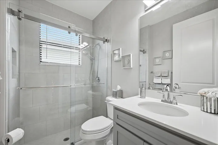 Glass-enclosed shower with tile surround and window