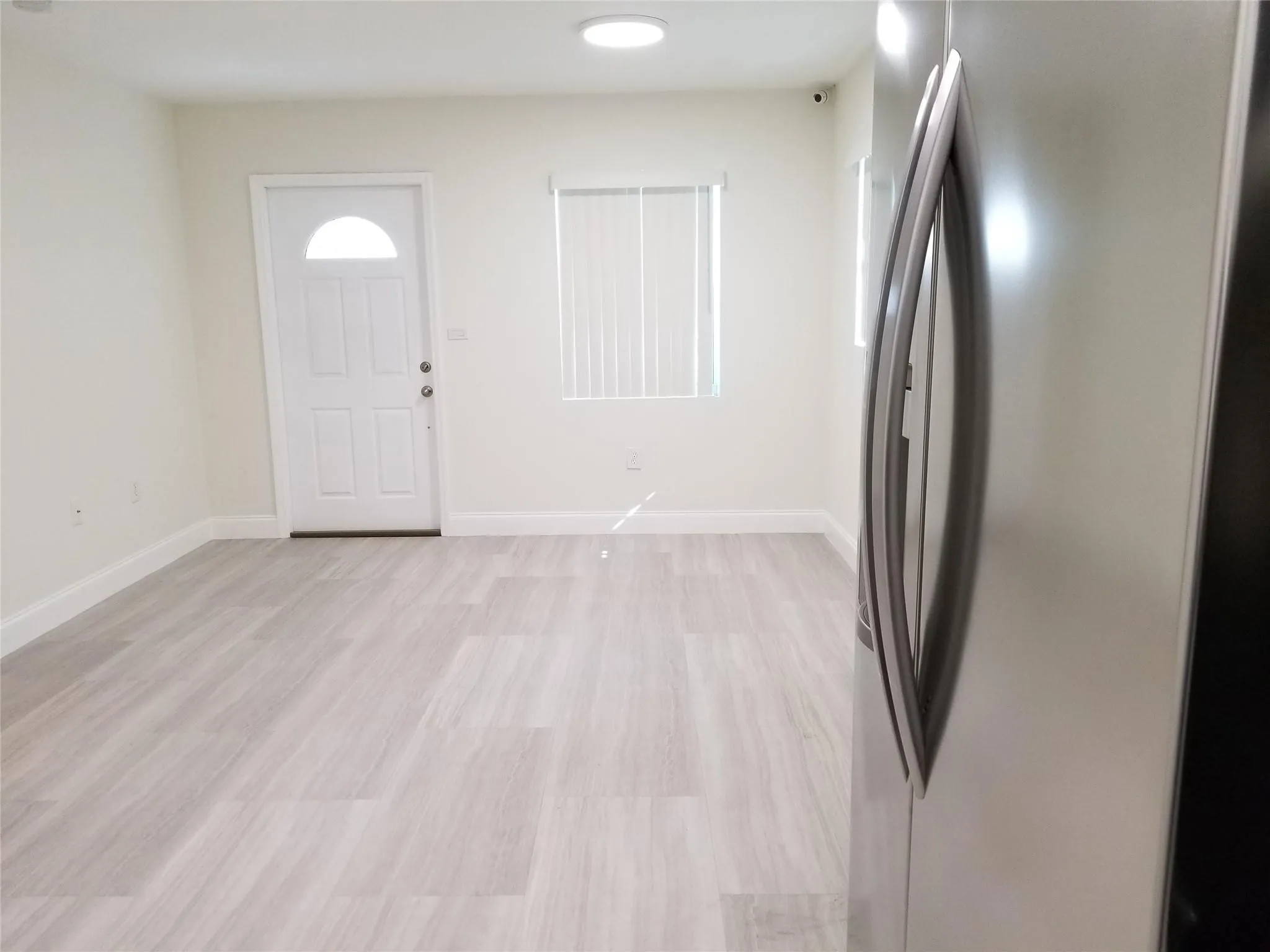 Light wood-finish flooring, white walls, and a recessed ceiling light