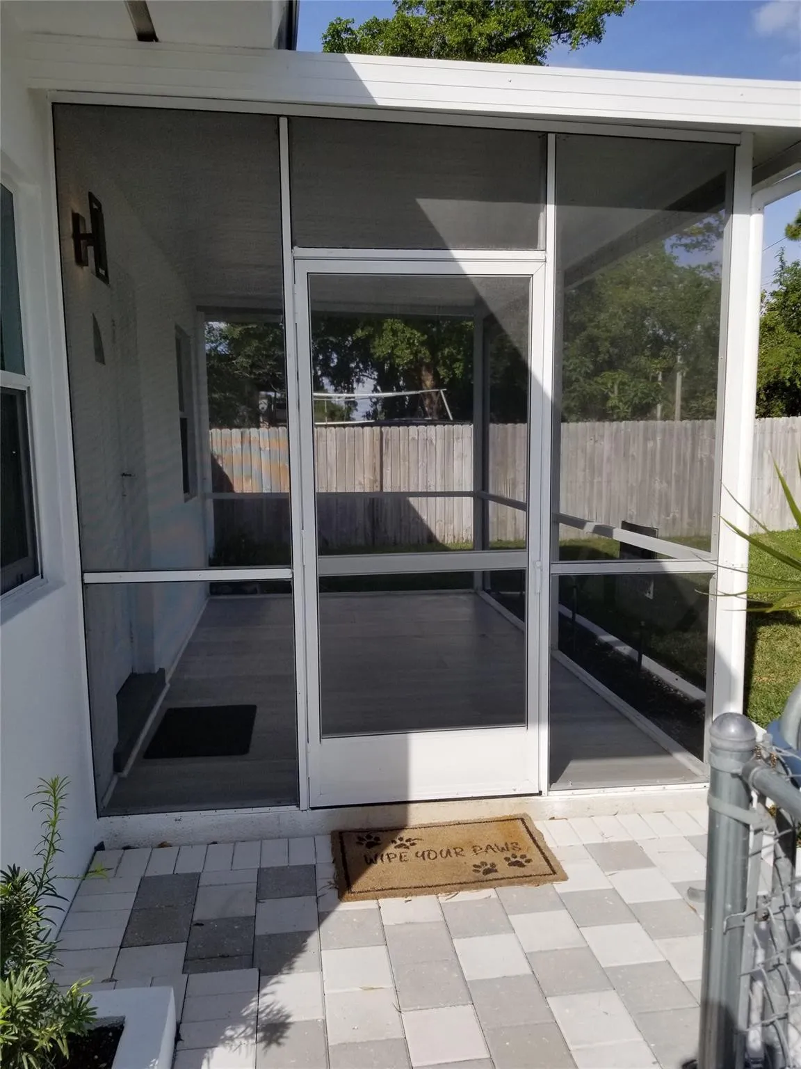 Screened outdoor patio featuring a white frame, wood-finish flooring, and a privacy fence background