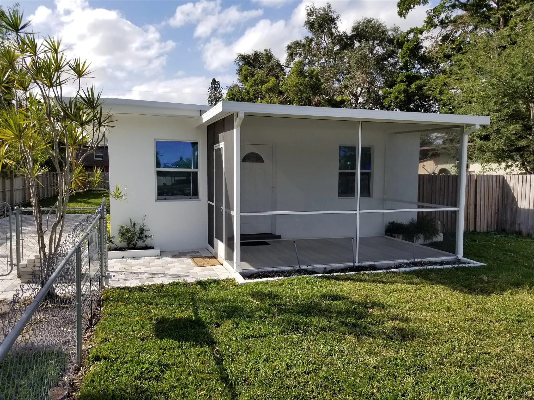 Screened porch with composite decking, white exterior finish, and a chain-link fence