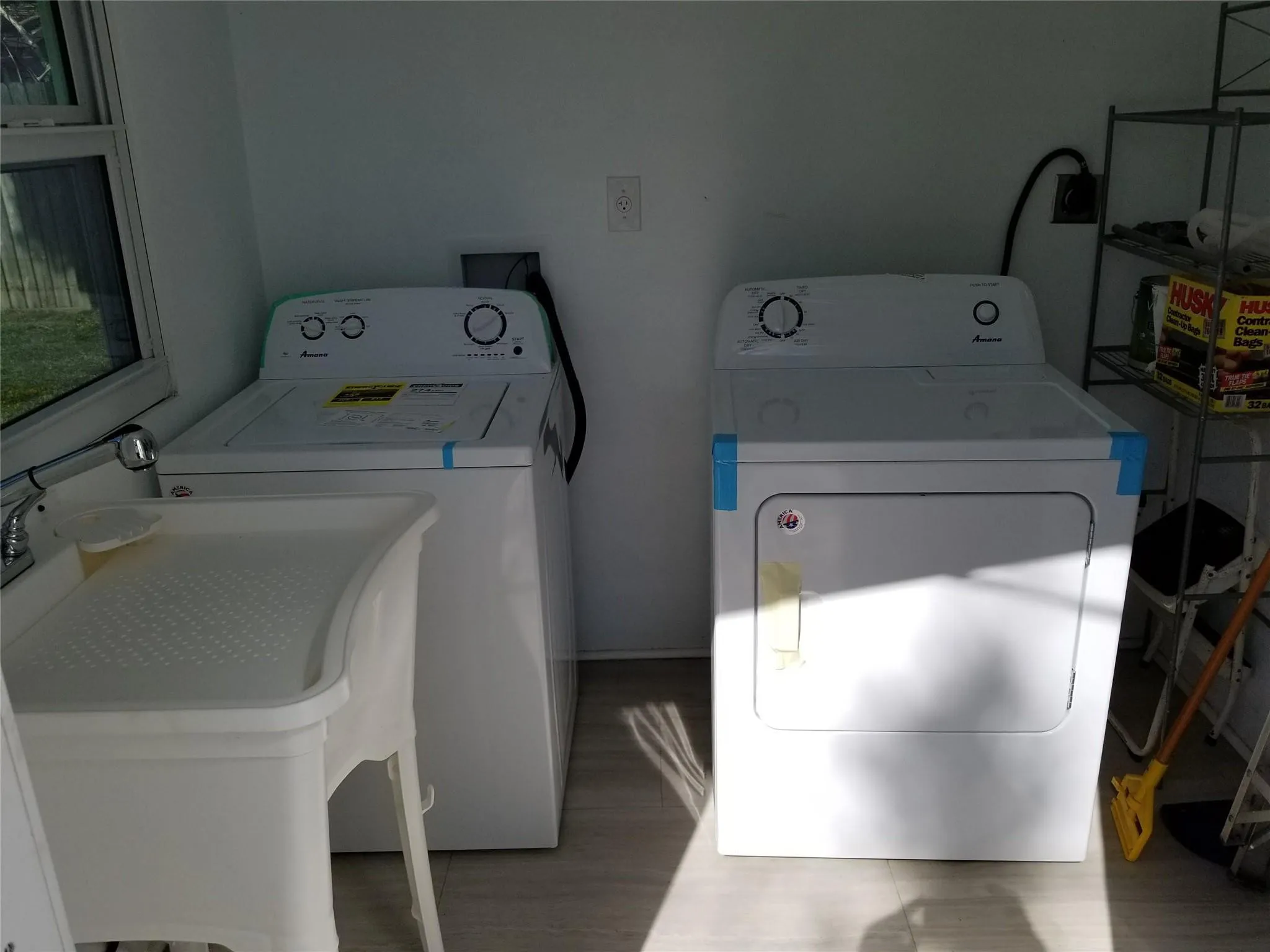 Utility area with a laundry sink, window, and wood-finish flooring