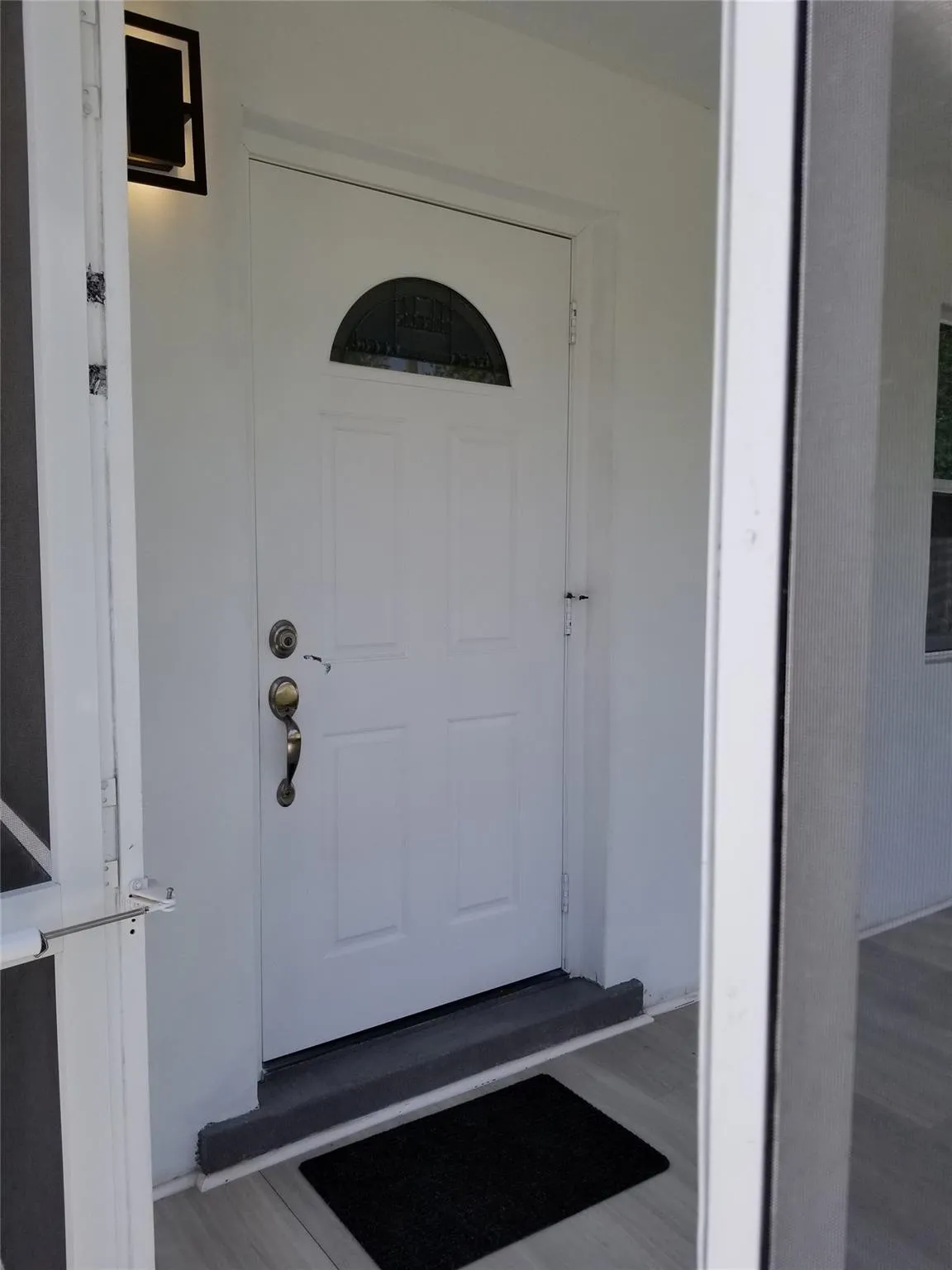 White panel door featuring a decorative transom window and brass hardware