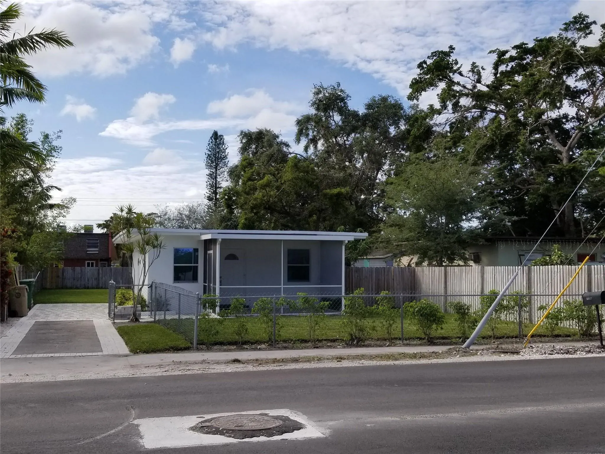 Single-story residence featuring a screened front porch, fenced front yard, and a paved driveway