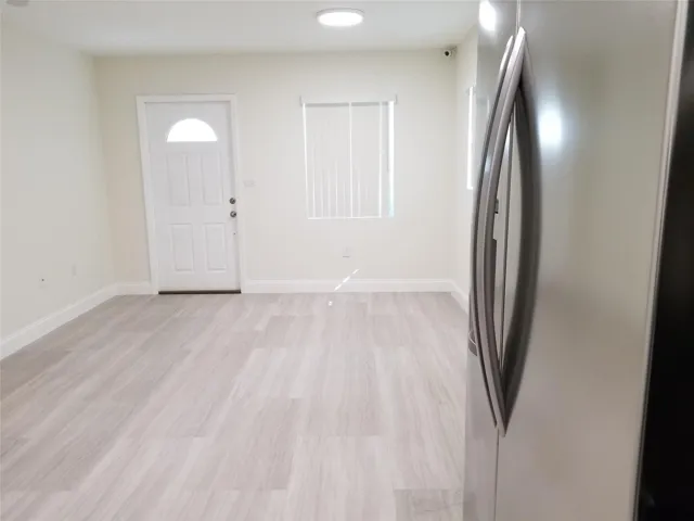 Light wood-finish flooring, white walls, and a recessed ceiling light