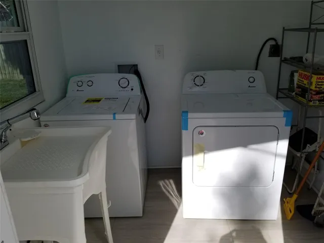 Utility area with a laundry sink, window, and wood-finish flooring