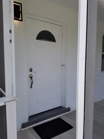 White panel door featuring a decorative transom window and brass hardware