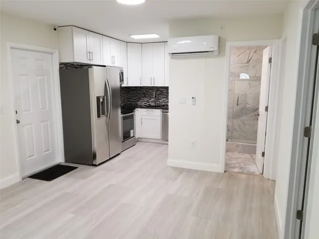 Kitchenette with white cabinetry, stainless steel appliances, and a dark mosaic tile backsplash