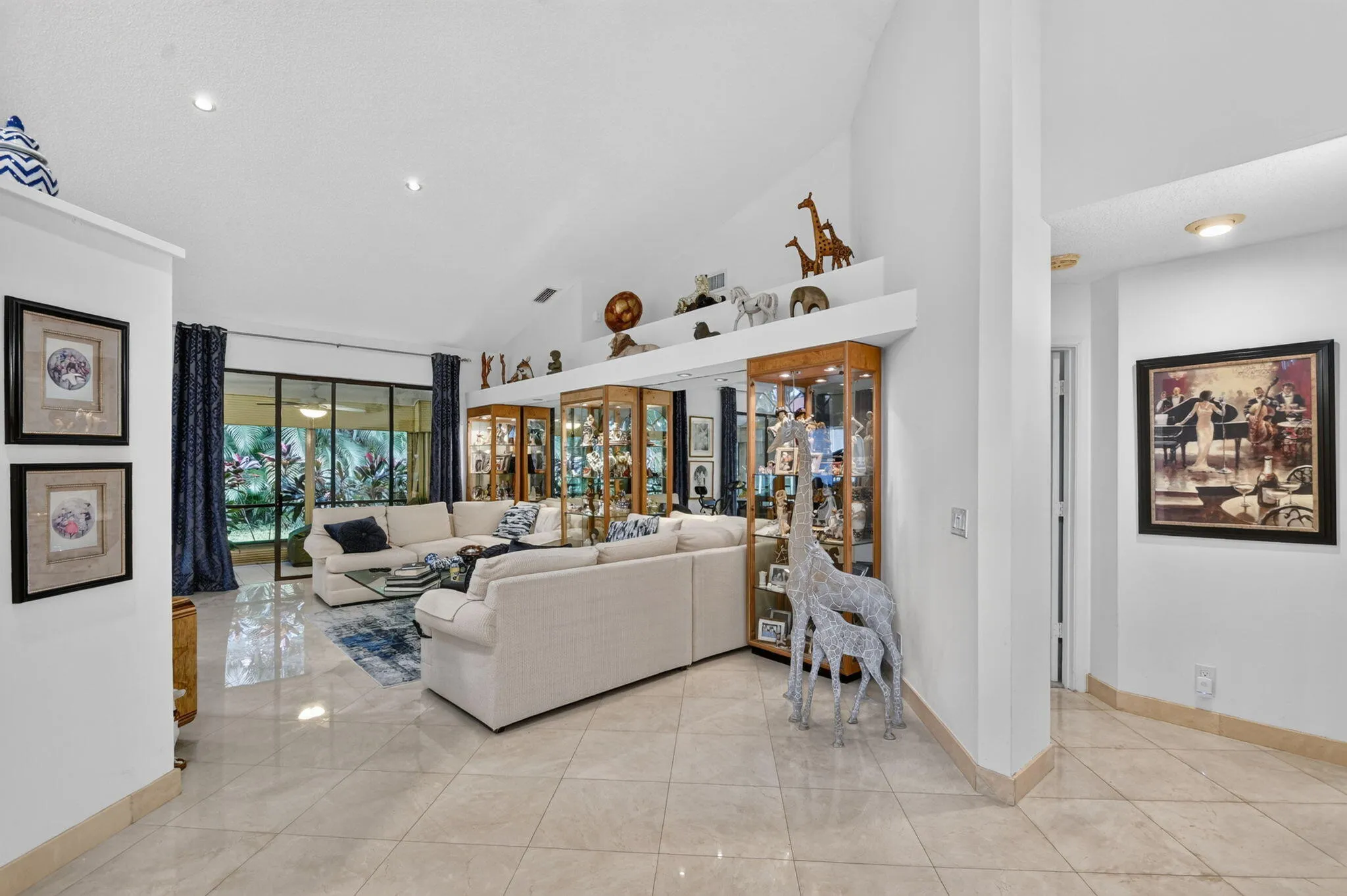 Vaulted ceiling, recessed lighting, large format tile flooring, built-in display cabinetry, and expansive glass doors
