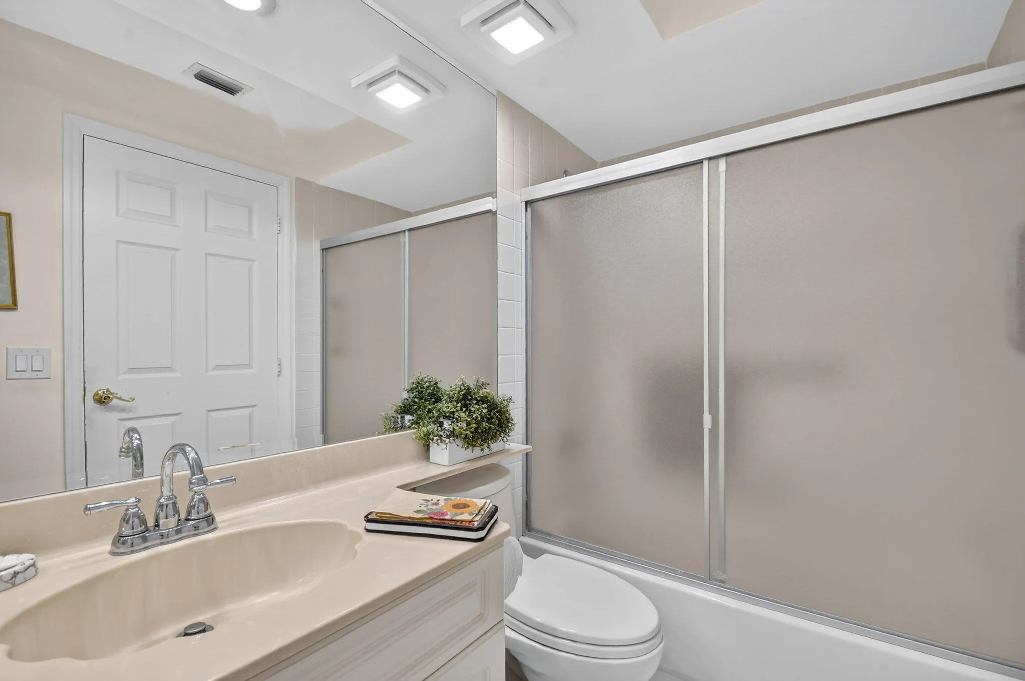 Vanity with an integrated sink, polished chrome faucet, and full-width mirror
