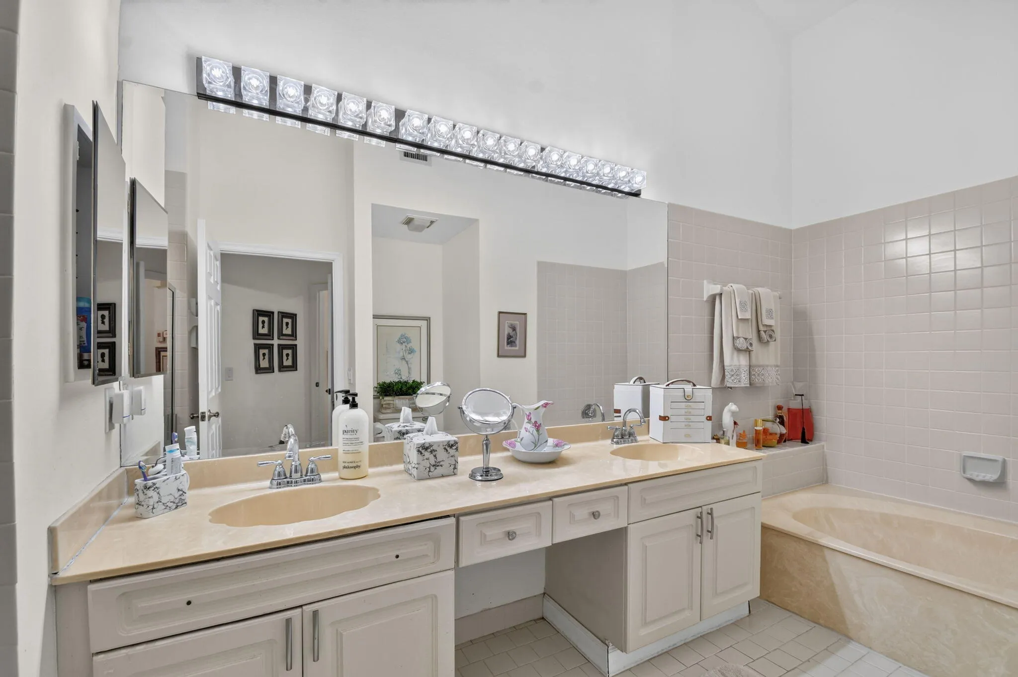 Dual undermount sinks set within a stone-finish countertop, expansive vanity mirror, and integrated vanity lighting