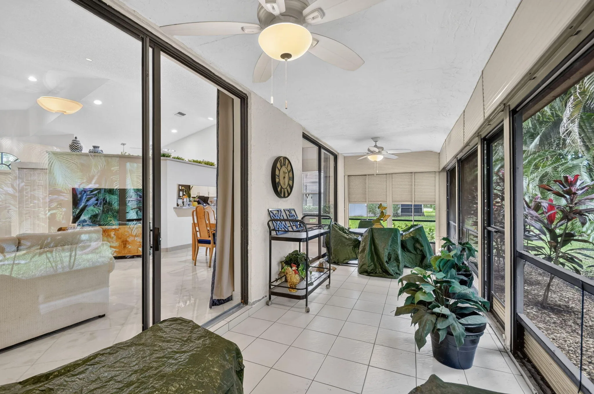 Screened patio with tile flooring, ceiling fans, and large sliding glass doors