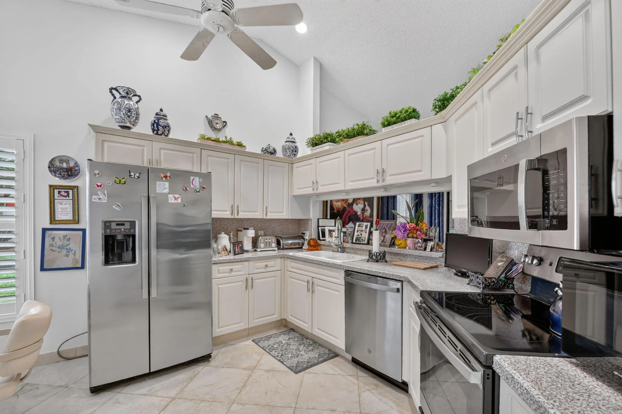 Kitchen featuring stainless steel appliances, light-toned cabinetry, a corner sink, and tiled flooring