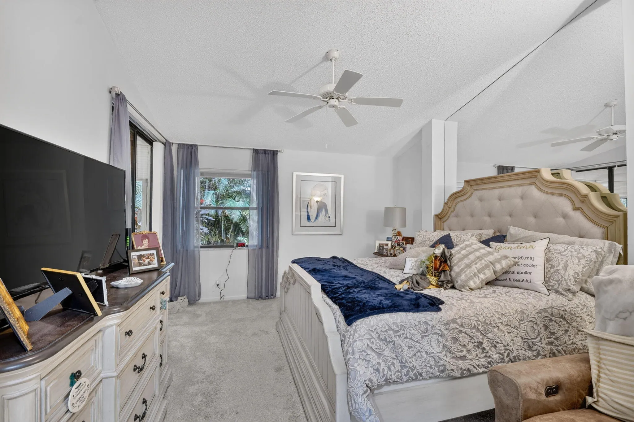 Vaulted ceiling with dual ceiling fans, carpeted flooring, and multiple windows with vertical blinds