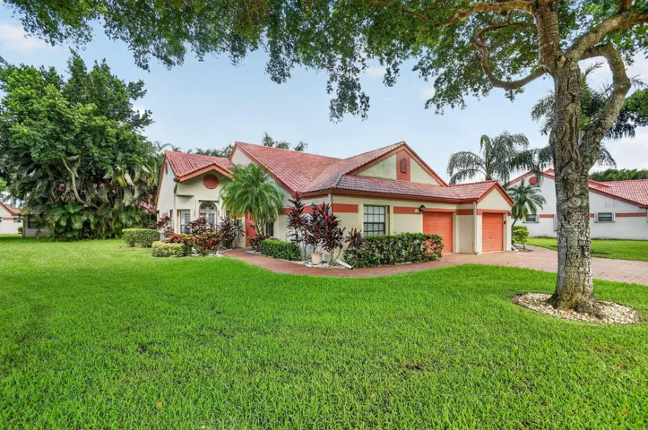 Exterior featuring a terracotta tile roof, stucco finish, attached two-car garage, and established landscaping