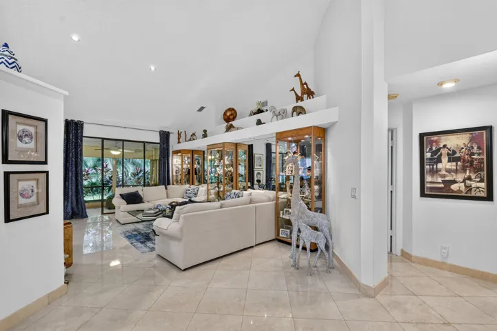 Vaulted ceiling, recessed lighting, large format tile flooring, built-in display cabinetry, and expansive glass doors