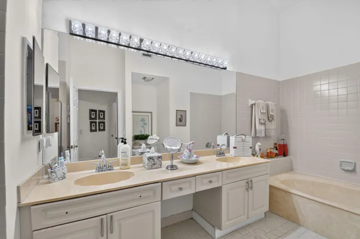 Dual undermount sinks set within a stone-finish countertop, expansive vanity mirror, and integrated vanity lighting