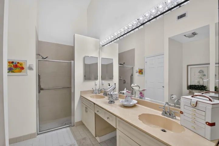 Double vanity with integrated sinks and ample countertop space, complemented by a large mirror and overhead lighting fixture