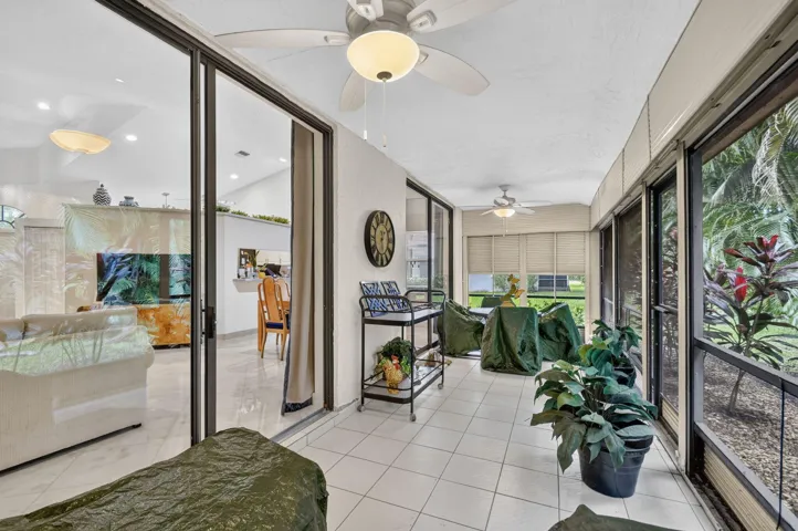 Screened patio with tile flooring, ceiling fans, and large sliding glass doors