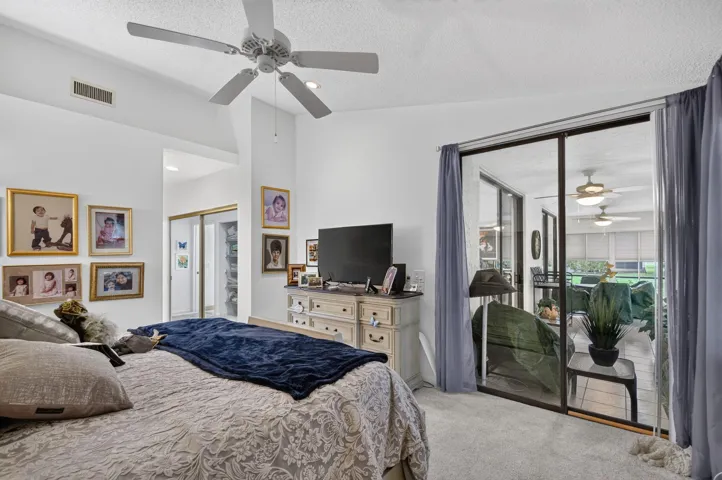 Vaulted ceilings, carpet flooring, a ceiling fan, and sliding glass doors