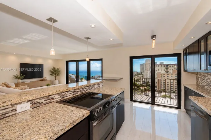 Kitchen featuring dark cabinetry, stone-finish countertops, mosaic tile backsplash, polished flooring, and dual glass sliding doors