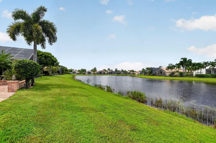 A graceful palm, lush green lawn and tranquil lake create a beautiful backdrop for this exceptional home.