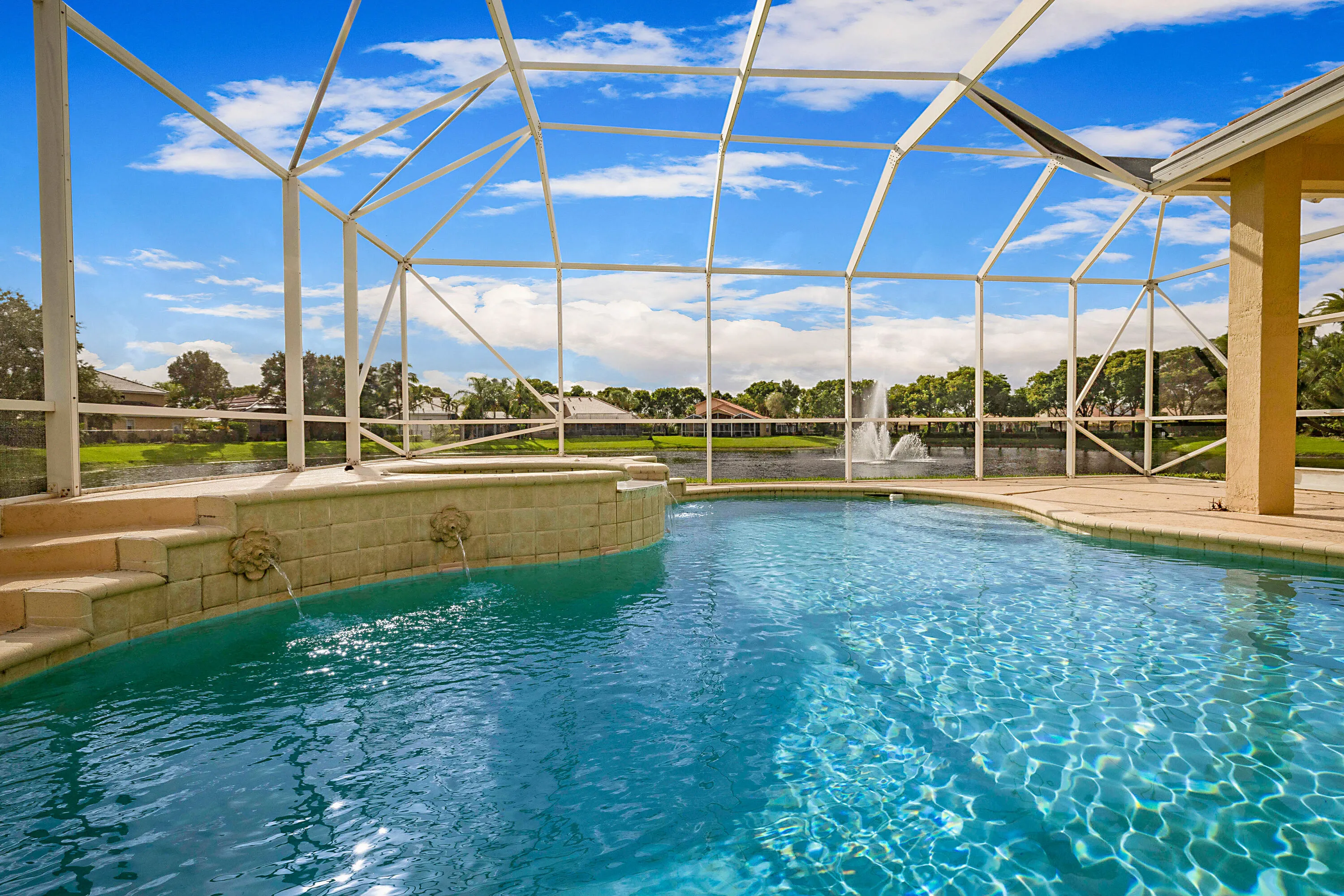 Screened enclosure with an in-ground pool, integrated spa, and decorative water features