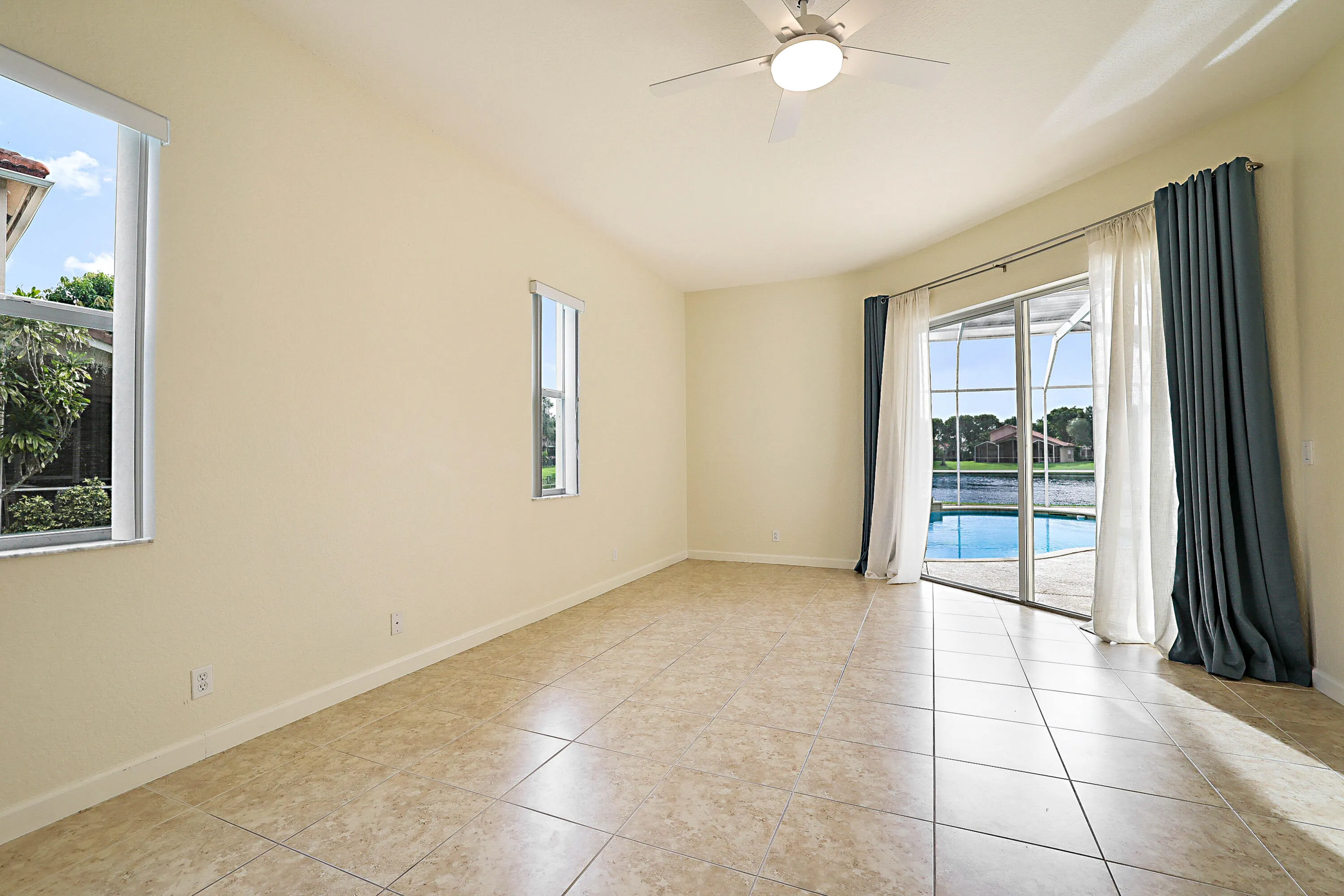 Spacious room featuring tile flooring, recessed ceiling lighting, and sliding glass doors with operable windows
